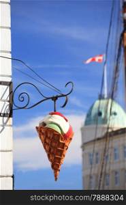 Big plastic ice cream cone sign over a clear blue sky on city street in Denmark