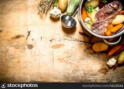 big pot of soup with beef and fresh vegetables. On wooden background.. big pot of soup with beef and fresh vegetables.