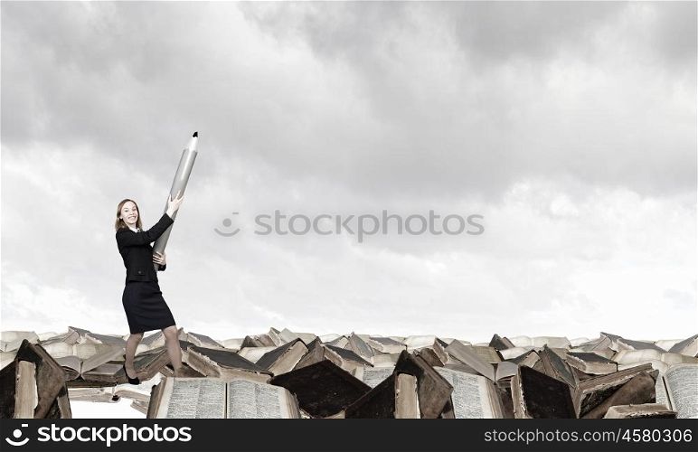 Big professional. Young businesswoman with big pencil standing on pile of books