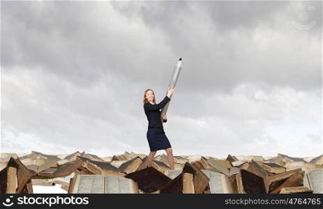 Big professional. Young businesswoman with big pencil standing on pile of books