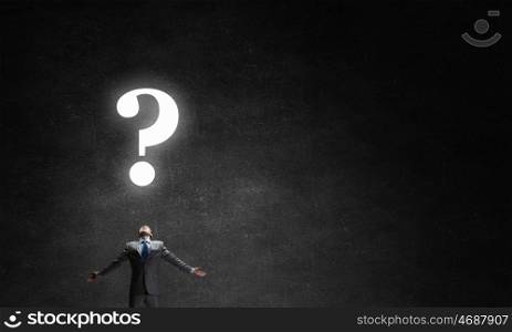 Big question. Businessman with hands spread apart looking above at big question