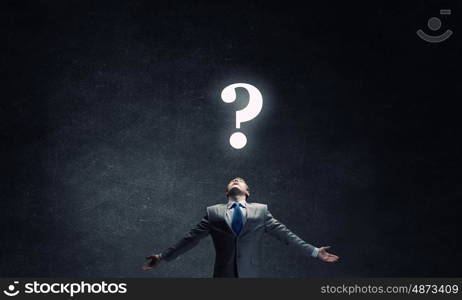 Big question. Businessman with hands spread apart looking above at big question