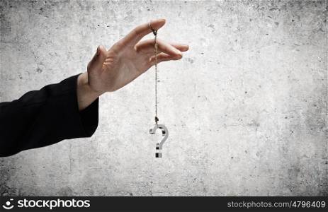 Big question. Close up of businessman hand and question sign hanging on finger