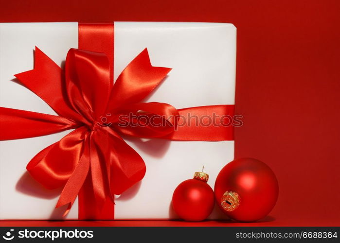 Big red bow on gift with red background and christmas balls