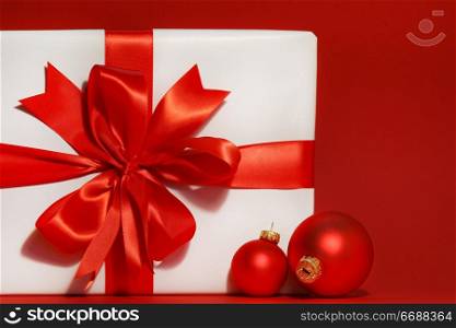 Big red bow on gift with red background and christmas balls