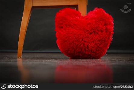 Big red heart shaped pillow on floor black background