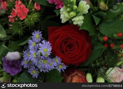 Big red rose in a flower arrangement with white and purple flowers
