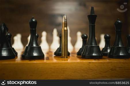 Big riffle bullet among chess pieces. Concept of weapon power