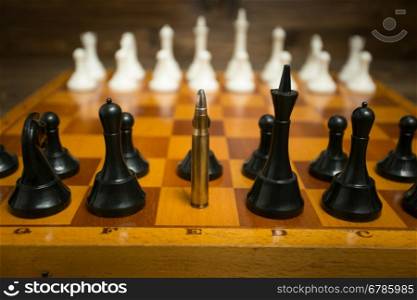 Big riffle bullet in row of chess pieces. Concept of weapon power