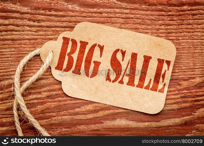 big sale sign - a paper price tag against rustic red painted barn wood - shopping concept