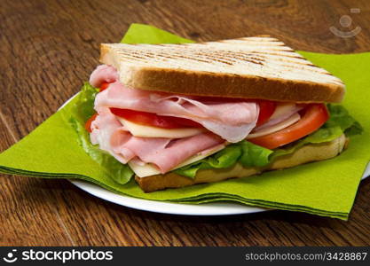 big sandwich with ham, cheese, tomatoes and salad on toasted bread