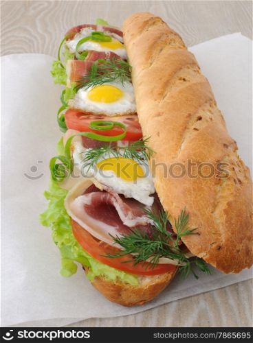 Big sandwich with ham, tomato and fried quail egg