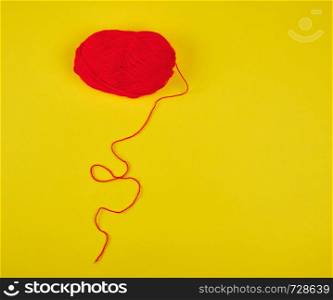 big skein of red wool on a yellow background, top view, copy space