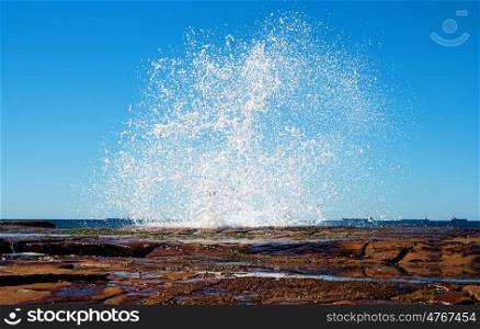 big splash as a wave hits the rocks at the coast