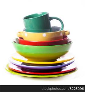 Big stack of different colors mugs and plate on white background, one above the another