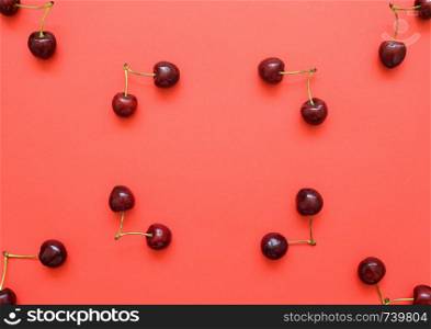 Big sweet cherry on a bright coral background. Cherries close up. Summer flat lay berry background. Top view cherry pattern.. Big sweet cherry on a bright background. Cherries close up. Summer flat lay berry background. Top view cherry pattern.