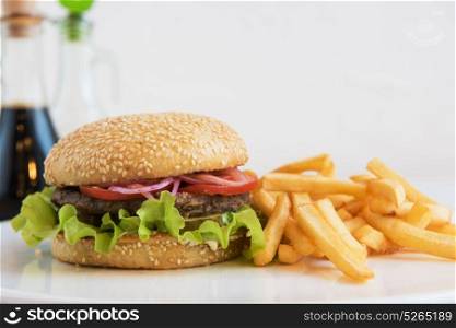 Big tasty burger. Tasty classical burger with fried potato on white table