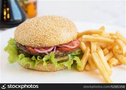Big tasty burger. Tasty classical burger with fried potato on white table