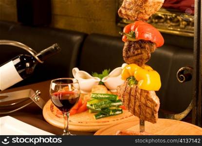 Big tasty roasted meat cuts at skewer on a decorated table