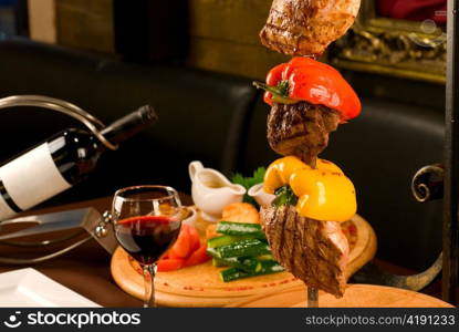 Big tasty roasted meat cuts at skewer on a decorated table