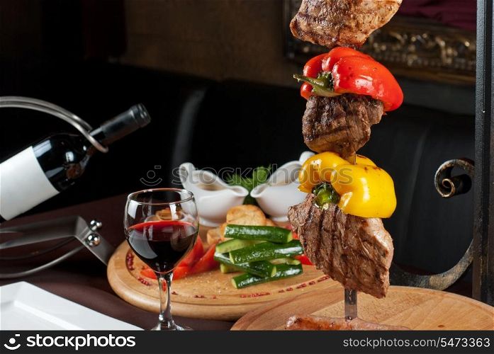 Big tasty roasted meat cuts at skewer on a decorated table