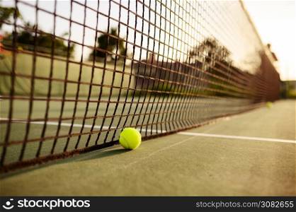 Big tennis ball at the net, nobody, outdoor court. Active healthy lifestyle, sport game with racket concept. Big tennis ball at the net, nobody, outdoor court