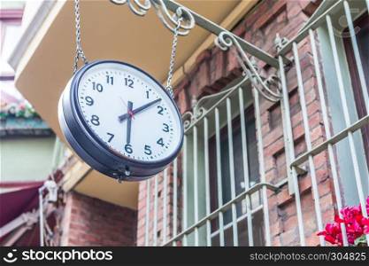 Big vintage old clock hanging with chain on a stone window . Big vintage old clock hanging with chain
