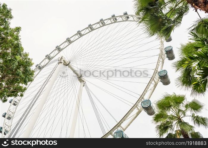 Big wheel in amusement park against of cloudy sky. View on ferris wheel from low perspective