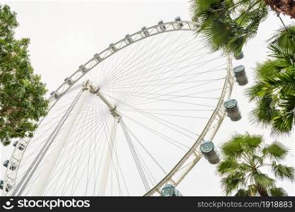 Big wheel in amusement park against of cloudy sky. View on ferris wheel from low perspective