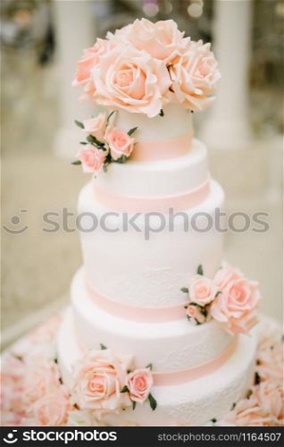 Big white wedding cake with fruit is on the table close up. Big white wedding cake with fruit is on the table