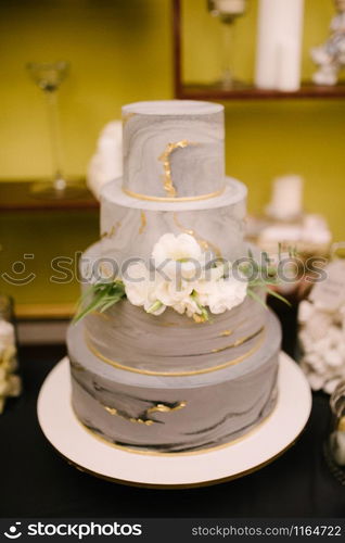 Big white wedding cake with fruit is on the table close up. Big white wedding cake with fruit is on the table