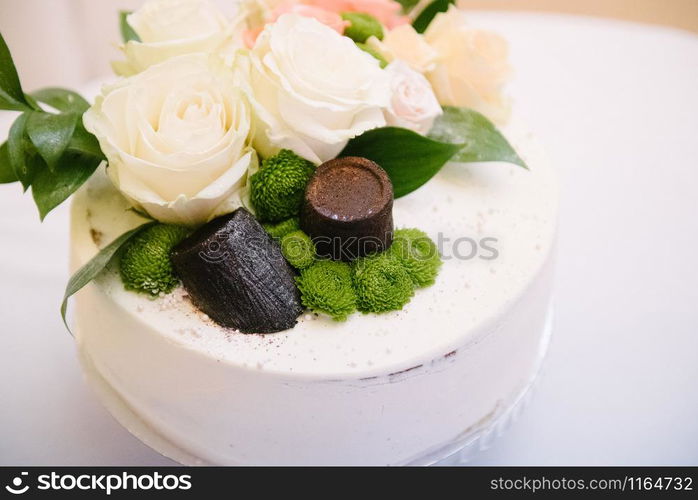 Big white wedding cake with fruit is on the table close up. Big white wedding cake with fruit is on the table