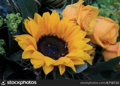 Big yellow sunflower and some yellow roses in a floral arrangement
