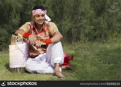 Bihu dancer sitting with a dhol