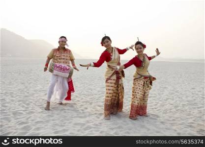 Bihu women dancing as Bihu man plays on a dhol