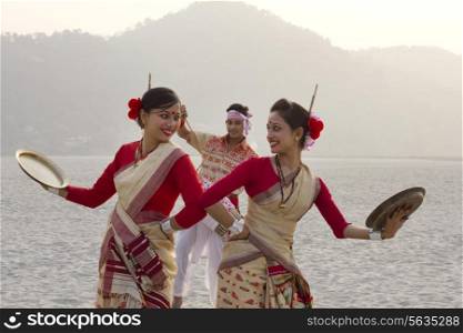 Bihu women dancing with brass plates