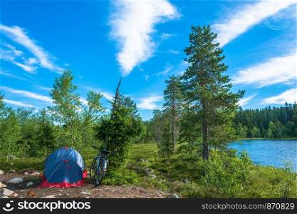Bike and tent on the shore of the lake on a summer day, Karelia, Russia.
