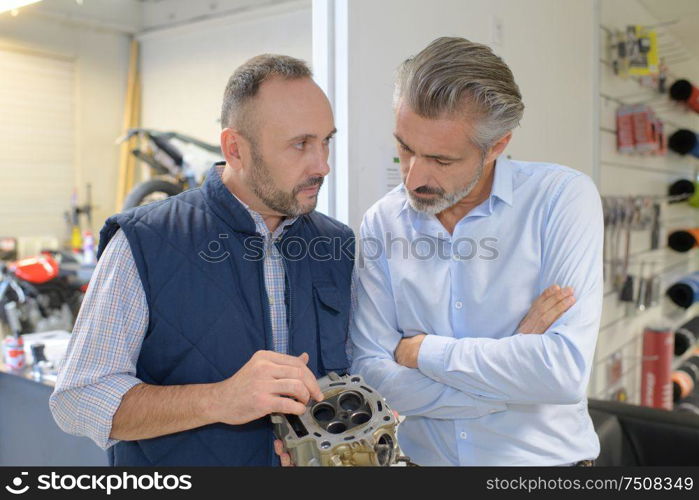 bike mechanic looking at four-valve cylinder head with client