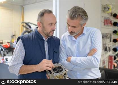 bike mechanic looking at four-valve cylinder head with client