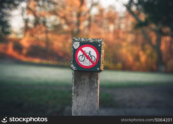 Bike restriction sign in a park in autumn with no bike riding allowed