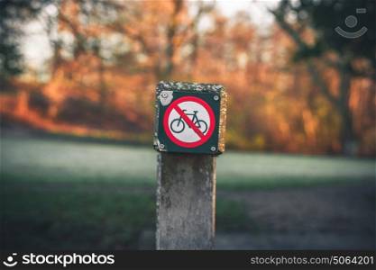 Bike restriction sign in a park in autumn with no bike riding allowed