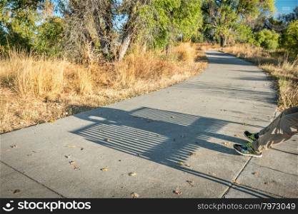 bike trail with a shadow of man resting on a bench - Poudre River Corridor Trail in northern Colorado, late summer