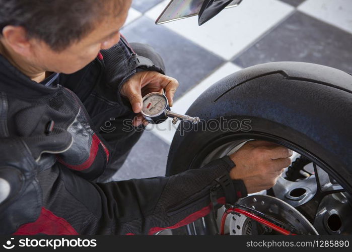 biker checking air pressure in rear wheel of big motorcycle