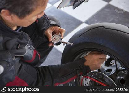 biker checking air pressure in rear wheel of big motorcycle