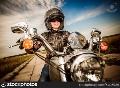 Biker girl in a leather jacket and helmet on a motorcycle