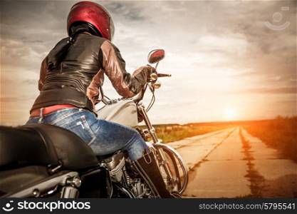 Biker girl in a leather jacket and helmet on a motorcycle. Focus on the fuel tank