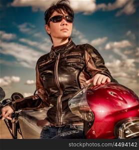 Biker girl in a leather jacket and sunglasses sitting on motorcycle