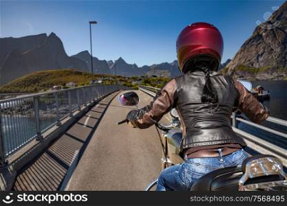 Biker girl rides on road in Norway.