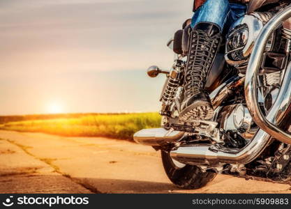 Biker girl riding on a motorcycle. Bottom view of the legs in leather boots.