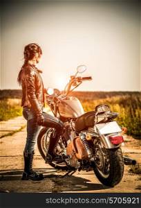 Biker girl stands on the road and looks into the distance